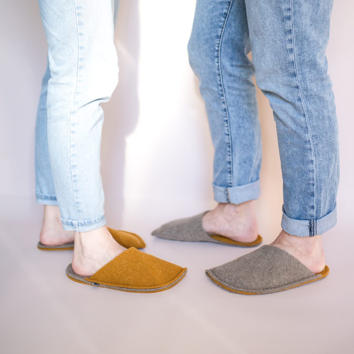 A couple wearing house slippers made of curcuma yellow and grayish brown wool felt