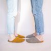 A couple wearing house slippers made of curcuma yellow and grayish brown wool felt