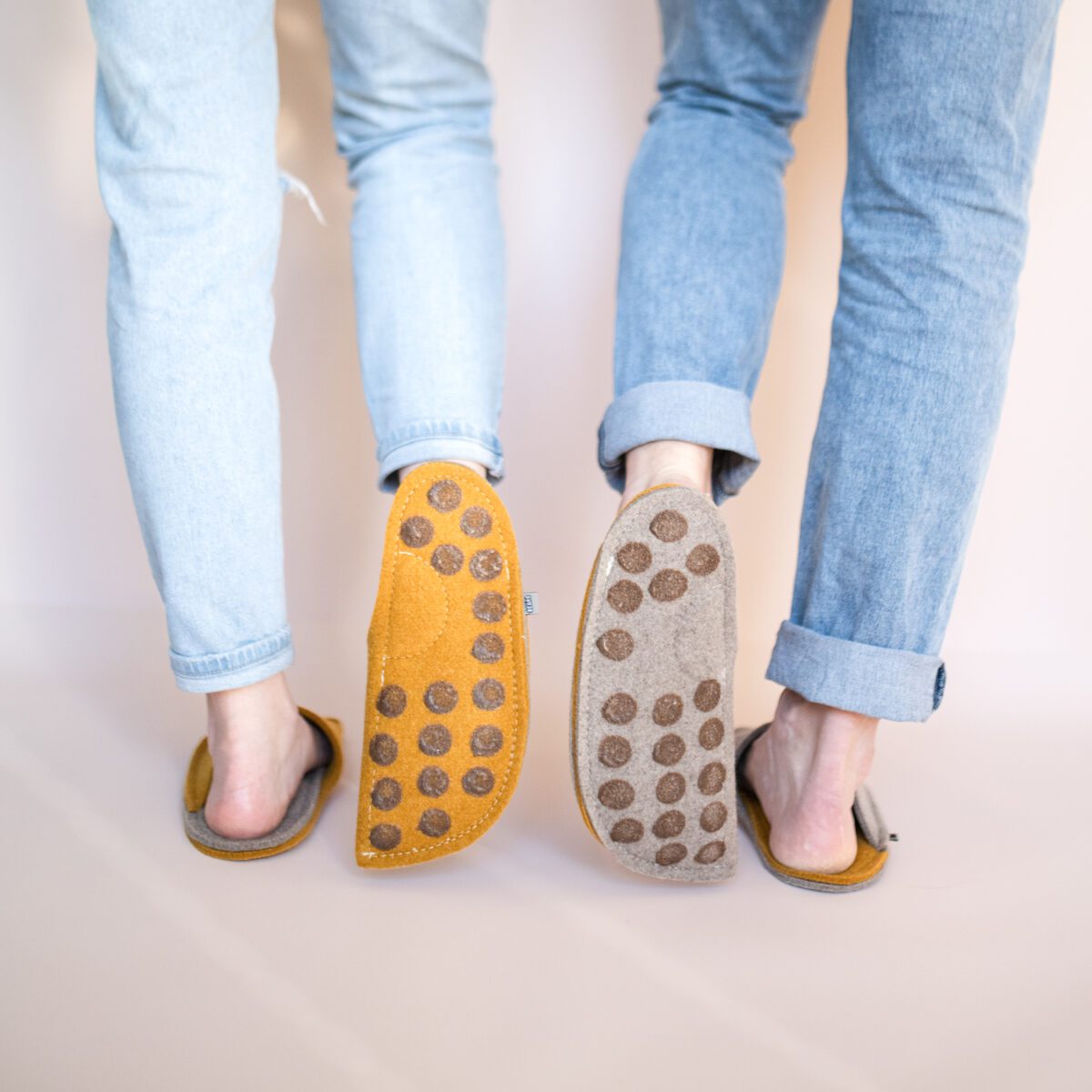 A couple wearing house slippers made of curcuma yellow and grayish brown wool felt