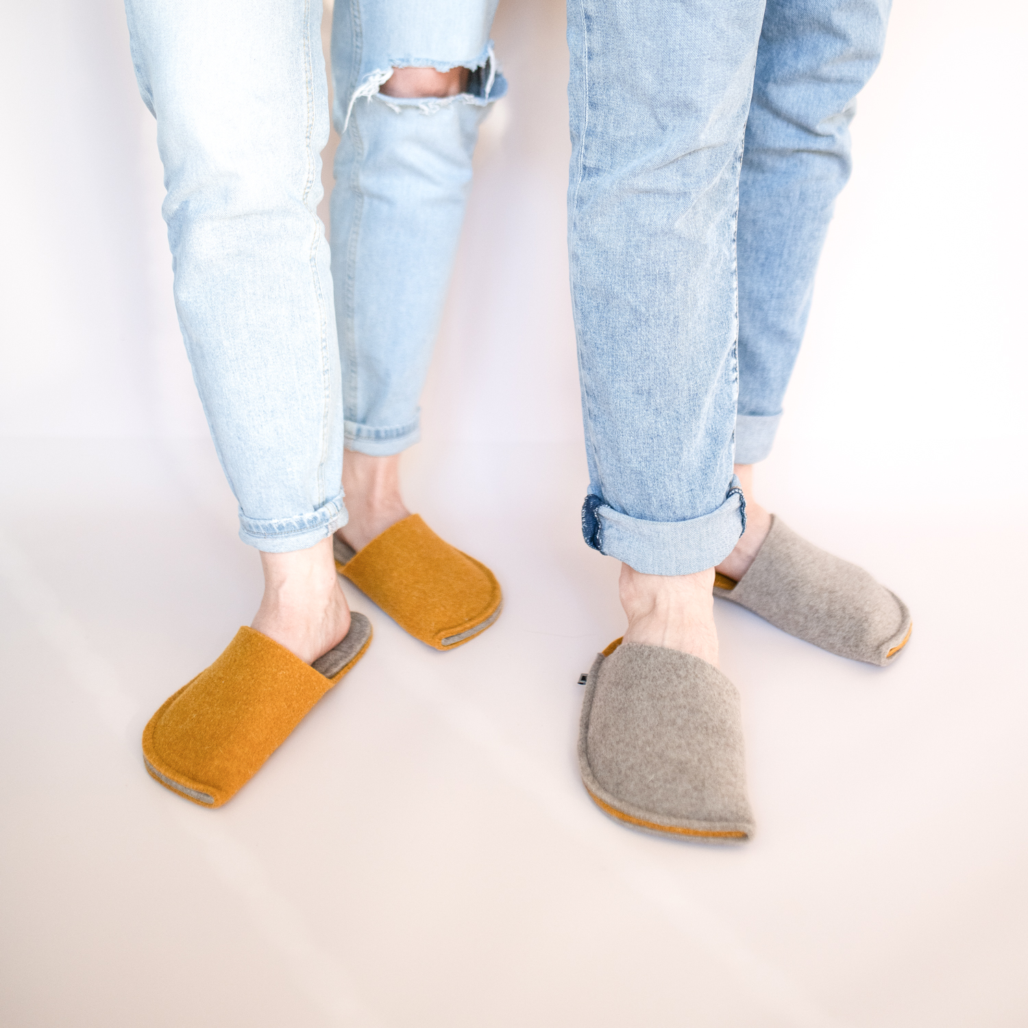 A couple wearing house slippers made of curcuma yellow and grayish brown wool felt