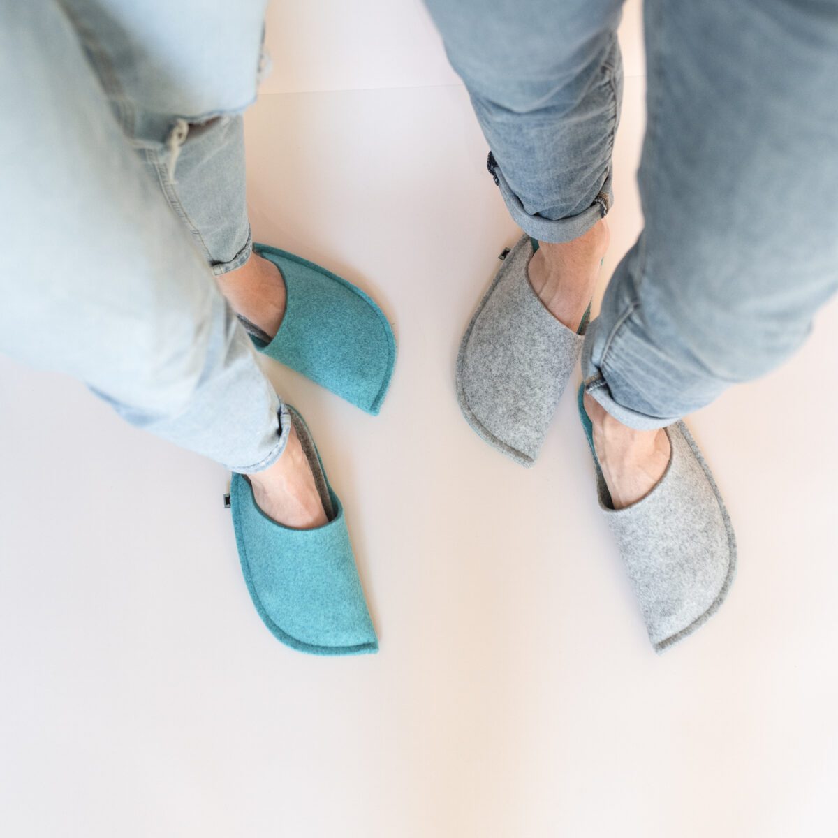 A man and a woman wearing slippers made of gray and blue wool felt.