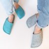 A man and a woman wearing slippers made of gray and blue wool felt.