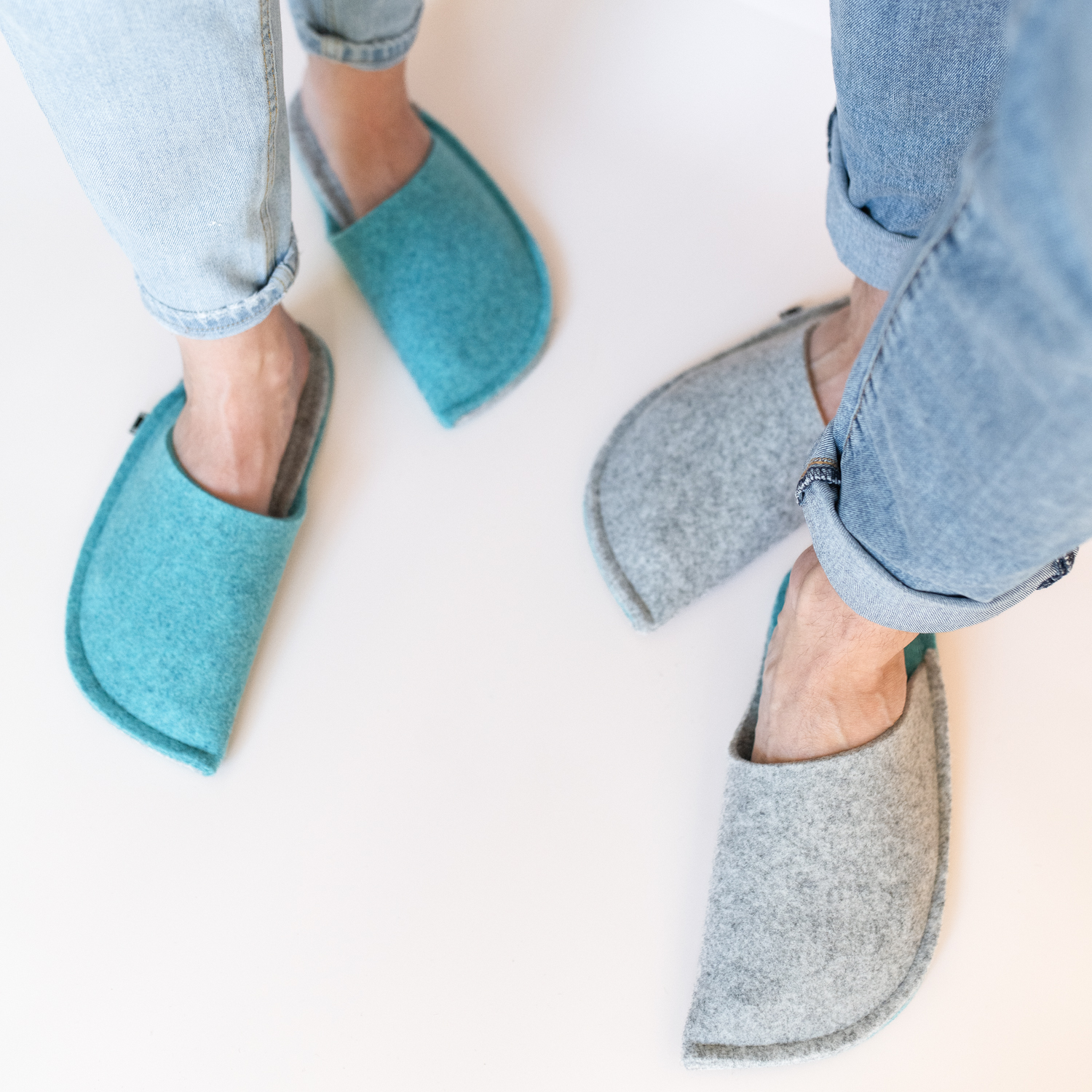 A man and a woman wearing slippers made of gray and blue wool felt.