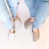 A couple wearing house slippers made of cream white and grayish brown wool felt