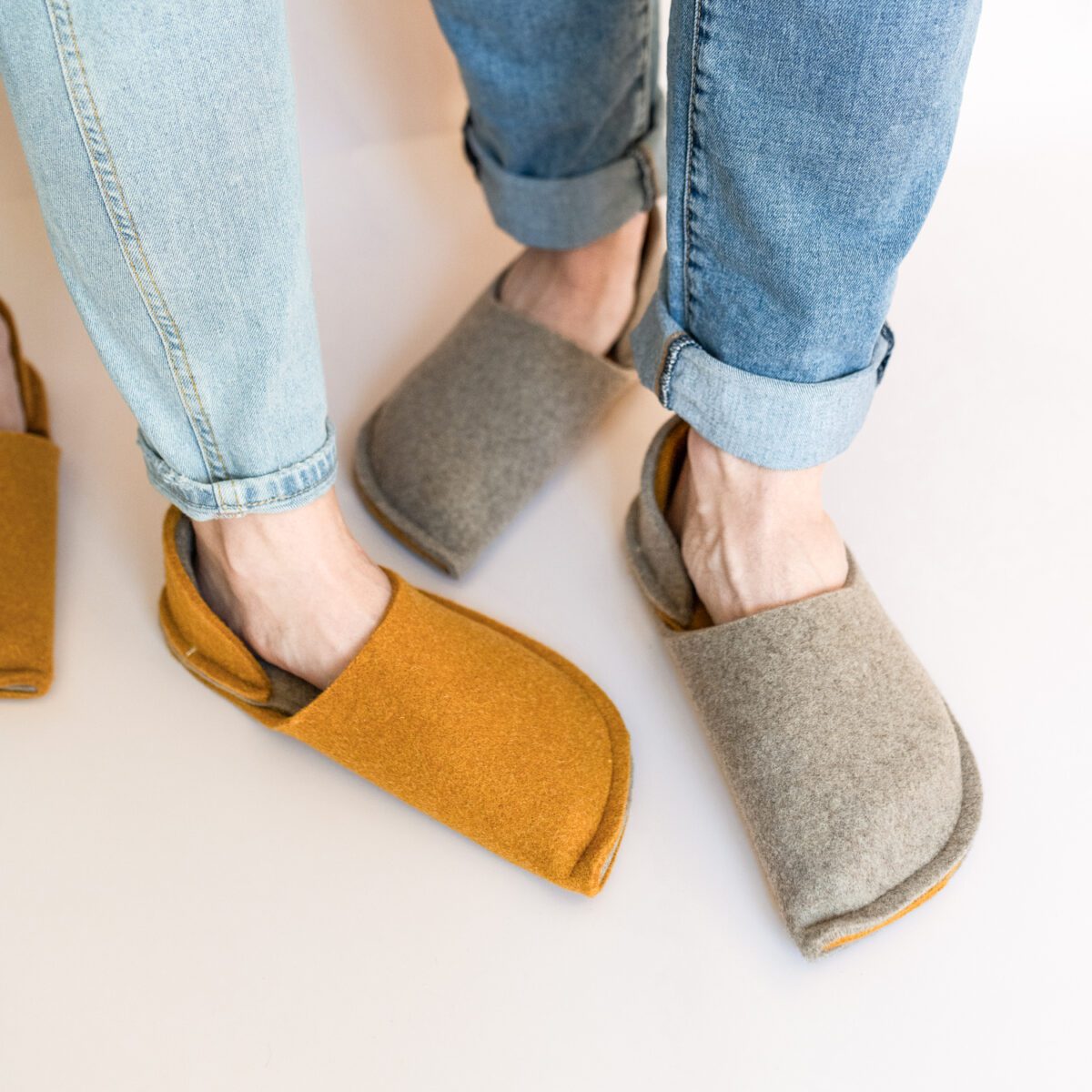 A couple wearing house slippers made of grayish brown and curcuma yellow wool felt