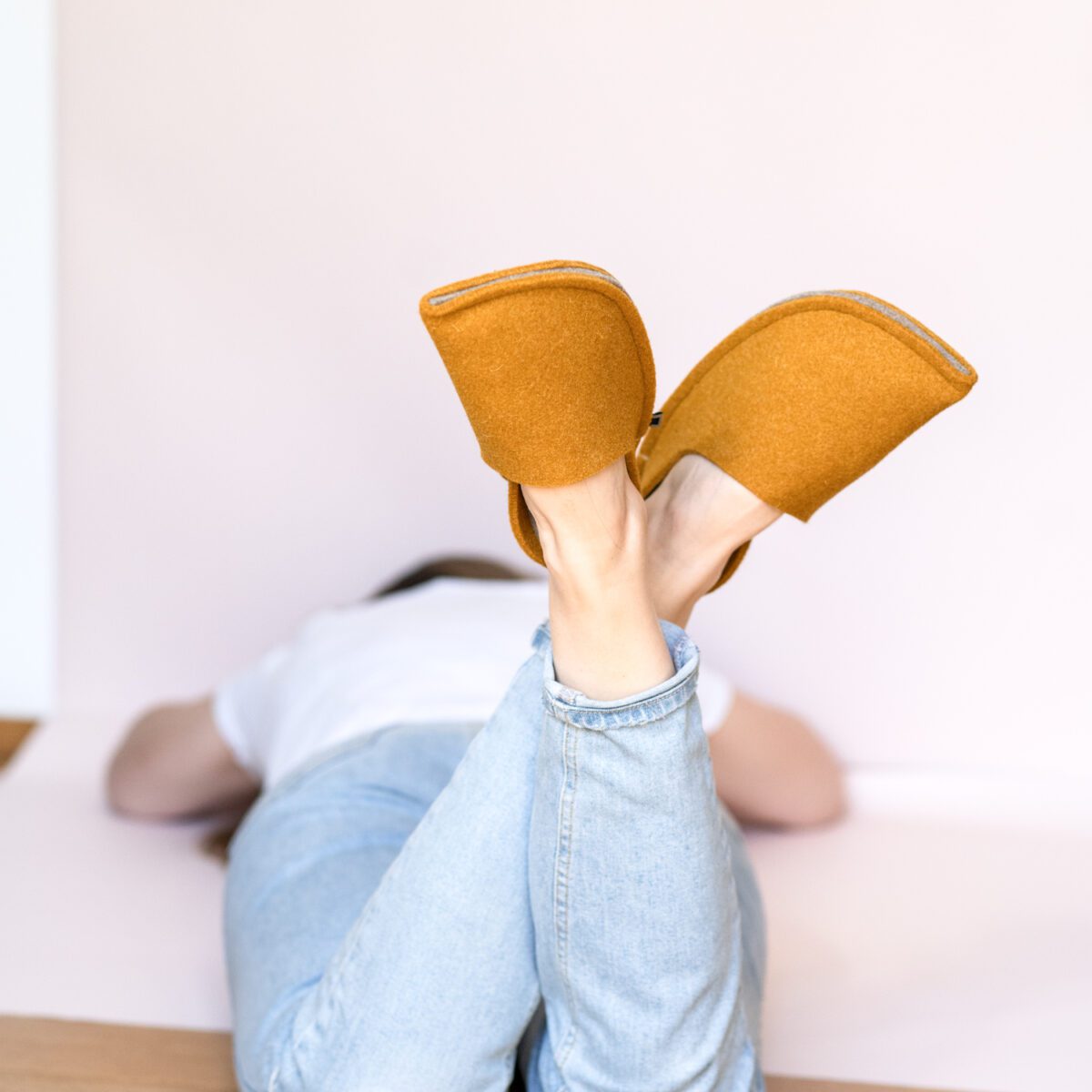 A woman wearing house slippers made of curcuma yellow and grayish brown wool felt