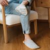 A man wearing house slippers made of light gray and peach yellow wool felt