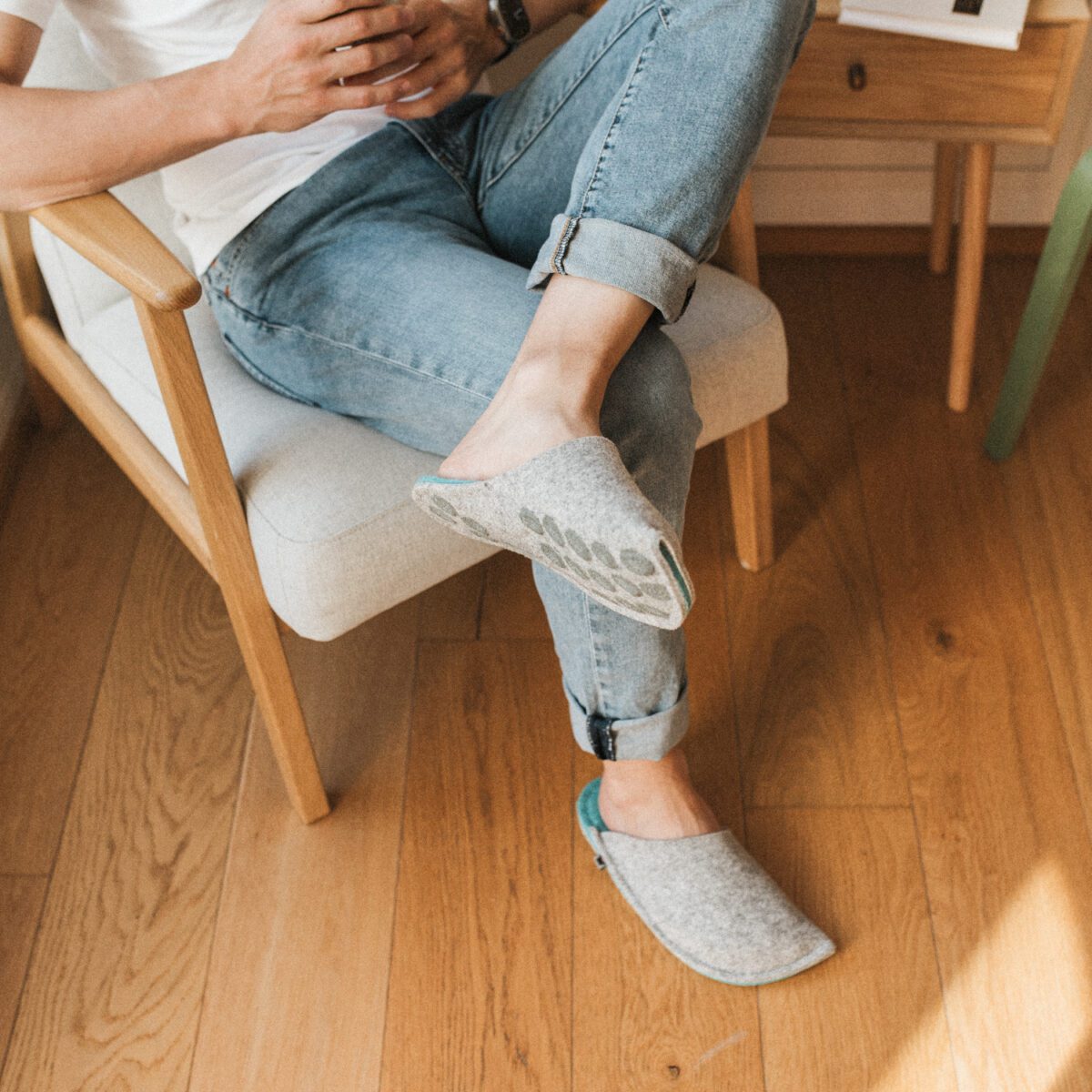 A man wearing slippers made of gray and blue wool felt.