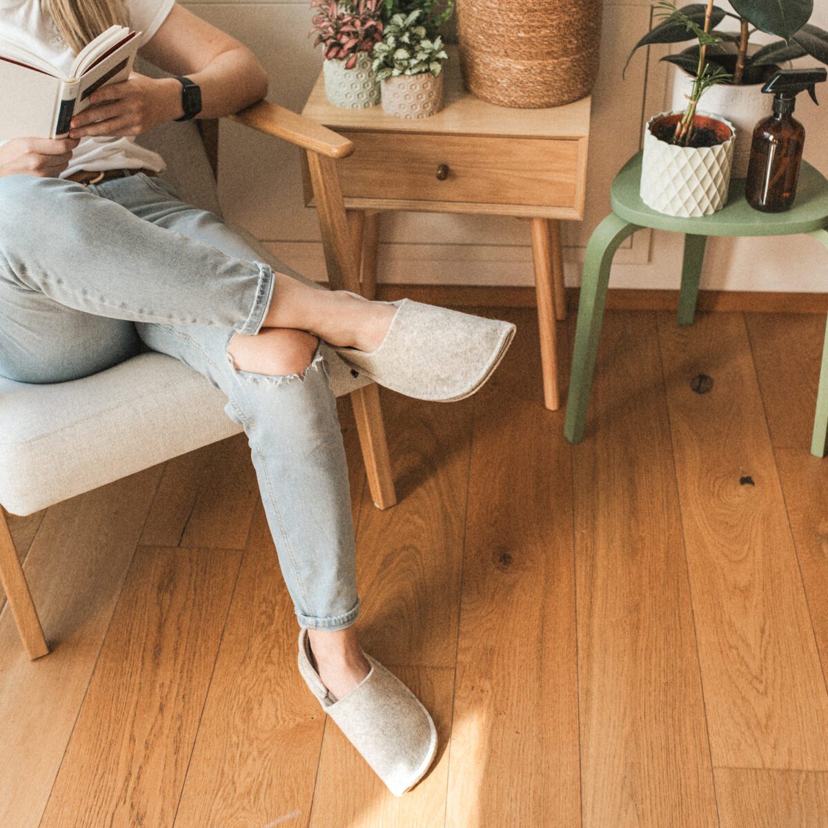 A woman wearing house slippers made of cream white and grayish brown wool felt