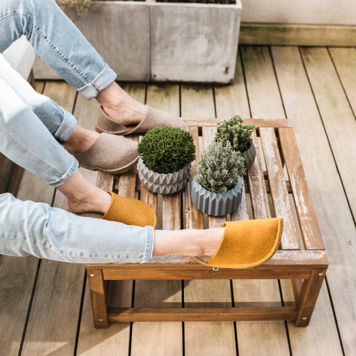 A couple wearing house slippers made of curcuma yellow and grayish brown wool felt