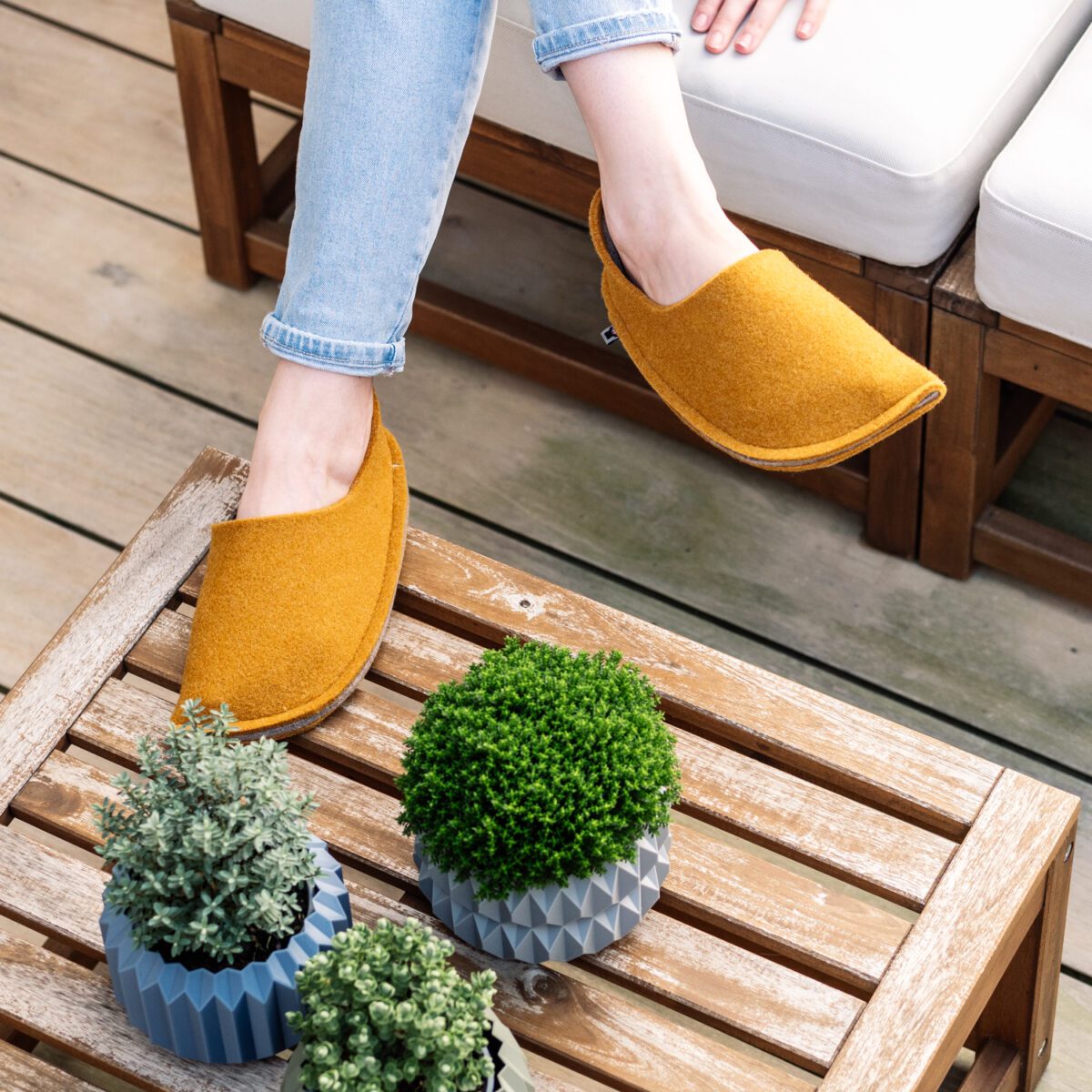 A woman wearing house slippers made of curcuma yellow and grayish brown wool felt